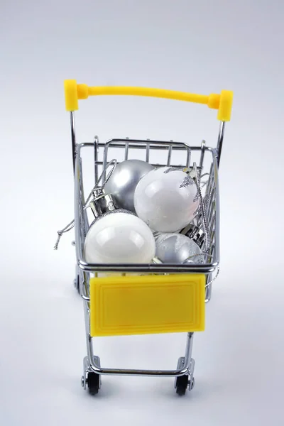Beyaz arka planda izole edilmiş noel topları olan alışveriş arabası. Noel konsepti.