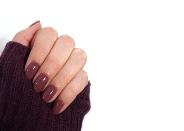 Beyaz arka planda menekşe rengi manikürlü mor kazak..