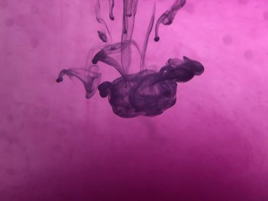 Suda mürekkep bulunan soyut pembe arkaplan.