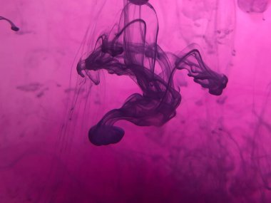 Suda mürekkep bulunan soyut pembe arkaplan.