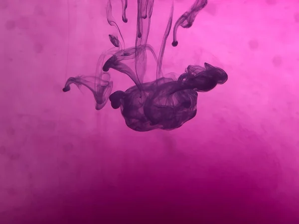 Suda mürekkep bulunan soyut pembe arkaplan.