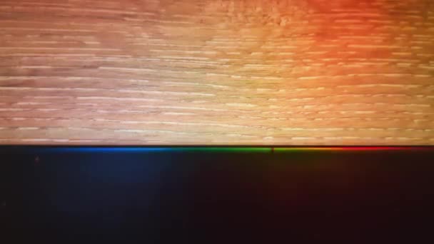 Farbwechselnde Lichter auf hellem Holzhintergrund. Farbenfrohe abstrakte moderne Kulisse. Glühende Dekoration. LED-Neonlampe — Stockvideo