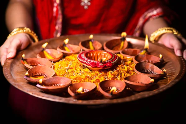 幸せなディワリの背景 伝統的な赤い布と宝石を身に着けているインドの女性や花嫁 点灯燃焼Diyaや粘土油ランプでいっぱいの法会を開催 花で飾られた — ストック写真