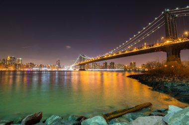 Geceleri bir arka plan üzerinde Manhattan ile Brooklyn Köprüsü