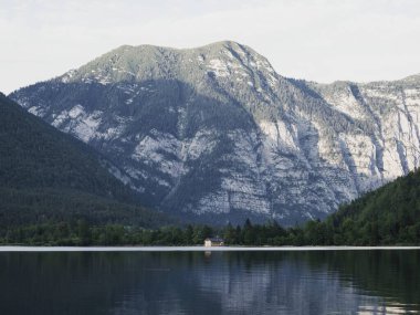 Hallstatt Gölü 'ndeki kayıkhanenin arka planında büyük bir dağ var.