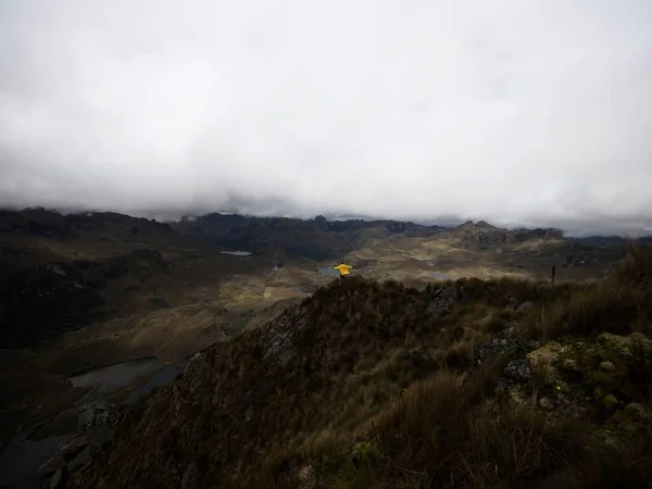Persona en chaqueta amarilla frente a cerros Andes tundra praderas lagos paisaje en el Parque Nacional El Cajas Cuenca Ecuador — Foto de Stock