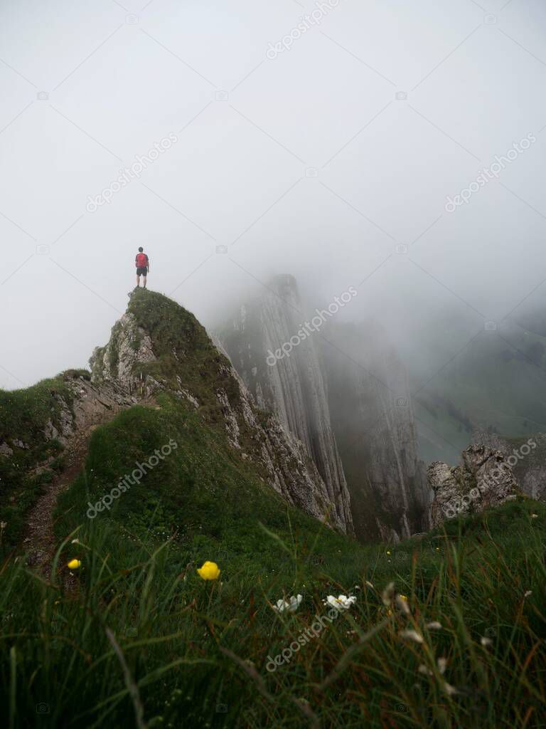 Hiker standing on Altenalptuerme mountain ridge swiss Alpstein alpine Appenzell Innerrhoden Switzerland