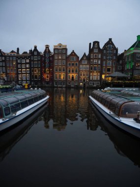 Hollanda 'nın orta Amsterdam' ında Damrak gracht 'ta tekneli ünlü dans evlerinin Alacakaranlık Manzarası