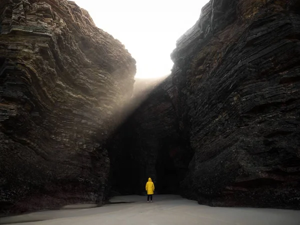 Person in gelber Jacke in der Nähe der massiven Felswand Bucht Praia als Catedrais Kathedralen Strand Ribadeo Galicien Spanien — Stockfoto