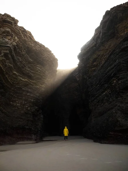 Person in gelber Jacke in der Nähe der massiven Felswand Bucht Praia als Catedrais Kathedralen Strand Ribadeo Galicien Spanien — Stockfoto