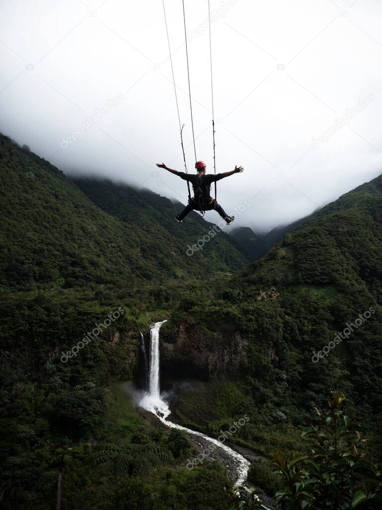 Tourist on giant swing adventure ride at Manto de la novia Bridal Veil waterfall Pastaza river Banos Tungurahua Ecuador