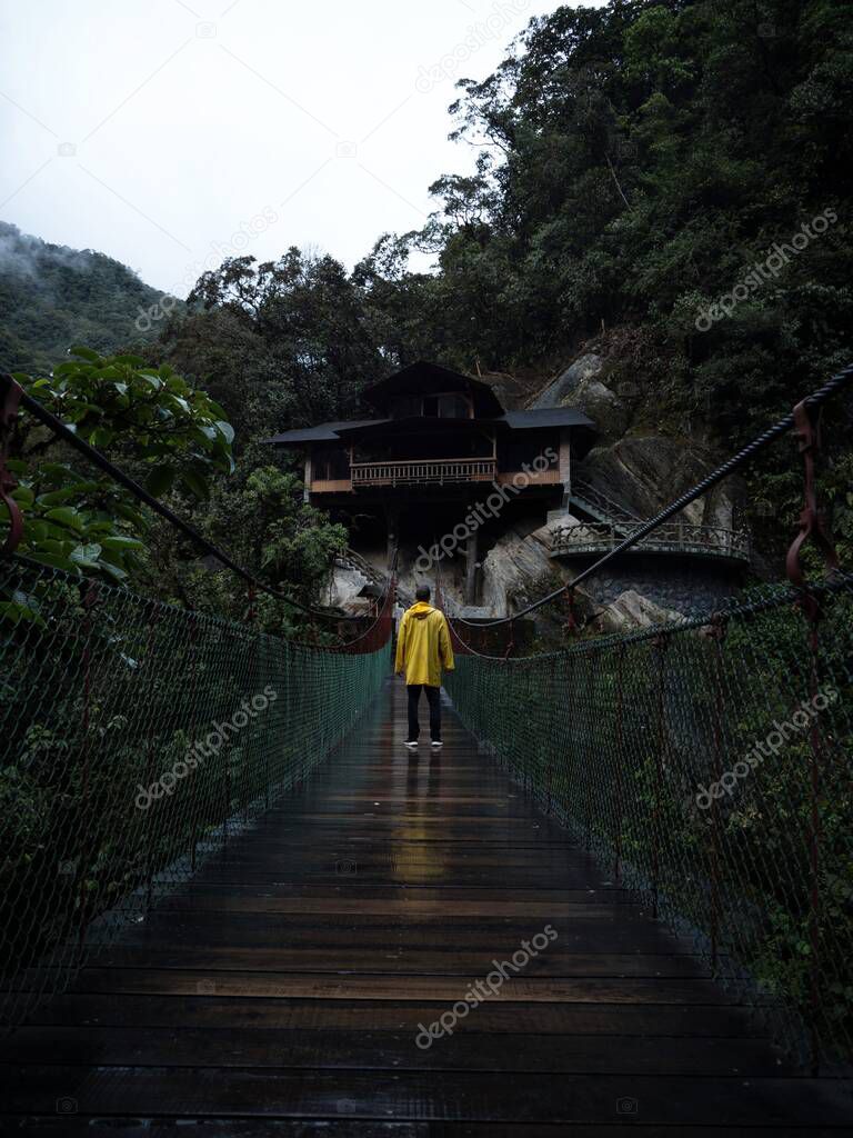 Yellow jacket person on swing bridge at Pailon del diablo Devils Cauldron Pastaza river Banos Tungurahua Amazon Ecuador