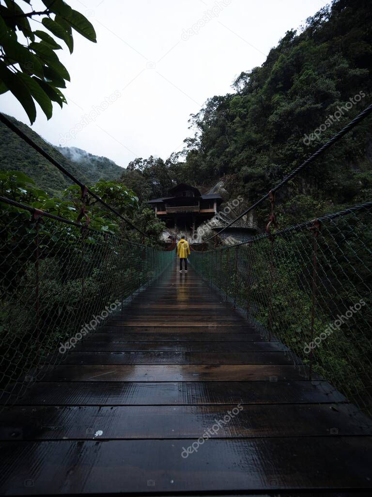Yellow jacket person on swing bridge at Pailon del diablo Devils Cauldron Pastaza river Banos Tungurahua Amazon Ecuador