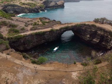 Pasih Uug 'un hava manzarası kırık plaj tropikal kaya kemer tünel uçurumu doğal köprü Nusa Penida Bali Endonezya