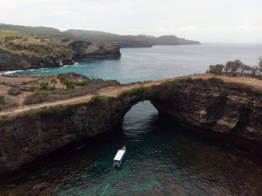 Pasih Uug 'un hava manzarası kırık plaj tropikal kaya kemer tünel uçurumu doğal köprü Nusa Penida Bali Endonezya