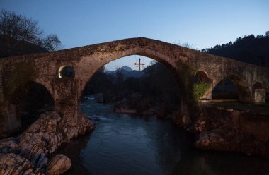Cangas de Onis Oriente Asturias İspanya 'daki Sella nehrinin üzerindeki kambur sırtlı taş köprü.