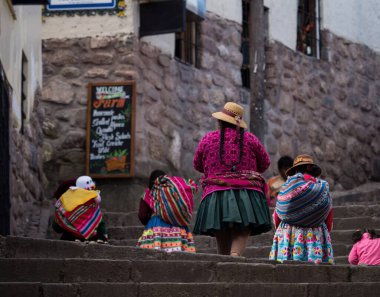 Cusco Peru 'da geleneksel el dokuması tekstil elbise kostümlü yerli quechua kadınları yürüyor.