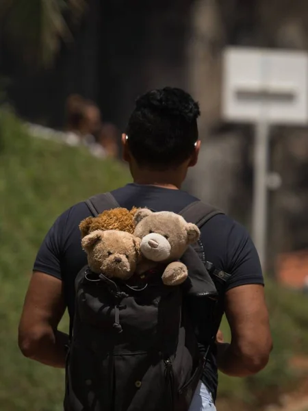 Homem adulto crescido com pelúcia ursinho de pelúcia brinquedo de pelúcia em mochila escola saco memórias de infância em Guatape Colômbia — Fotografia de Stock