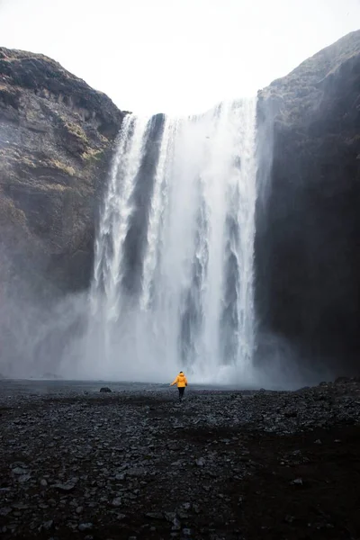 在冰岛南部Skogar附近著名的宽Skogafoss悬崖瀑布Skoga河的黄色夹克游客 — 图库照片