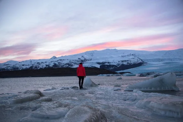 Czerwona kurtka turysta w górach lodowych w lagunie jeziora Fjallsarlon w lodowcu Vatnajokull Fjallsjokull śnieg zima Islandia — Zdjęcie stockowe
