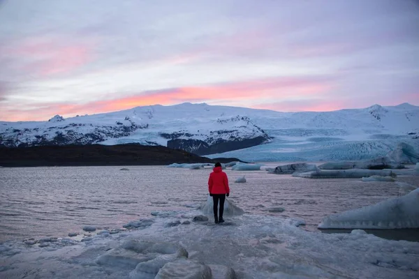 Czerwona kurtka turysta w górach lodowych w lagunie jeziora Fjallsarlon w lodowcu Vatnajokull Fjallsjokull śnieg zima Islandia — Zdjęcie stockowe