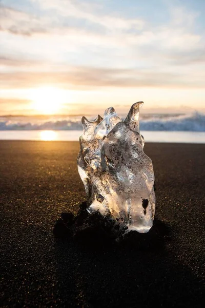 Parte de cristal de hielo pieza iceberg fragmento glacial en la arena negra olas del océano puesta de sol Diamond Beach Jokulsarlon Islandia del Sur — Foto de Stock