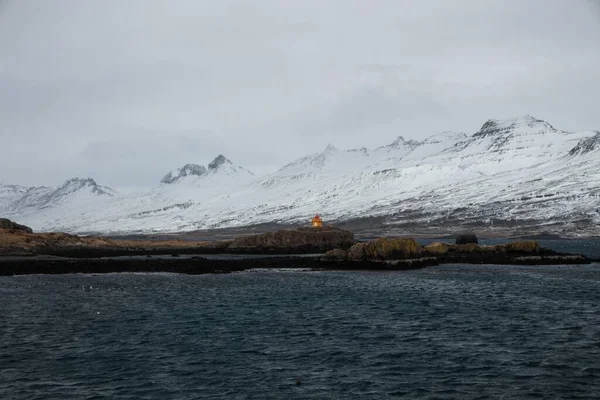 Vinterpanorama över orange Aedarstein fyr Aedarsteinsviti på stenig fjord ocean kust Djupivogur sydöstra Island — Stockfoto