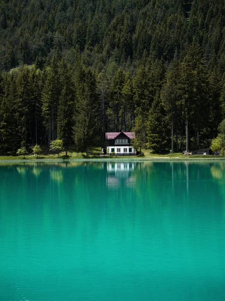 Old rustic house bright blue turquoise alpine mountain lake Lago di Dobbiaco Toblacher See Dolomites South Tyrol Italy — Stock Photo, Image