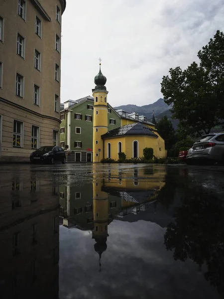Lienz Doğu Tyrol Avusturya 'daki sarı Heiliger Antonius kilisesinin su birikintisi ayna görüntüsü Avrupa' yı kaplıyor — Stok fotoğraf