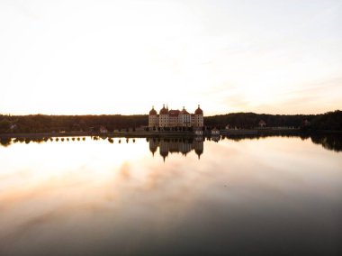 Schloss Moritzburg Barok kalesinin Saksonya Almanya 'sındaki Schlossteich gölü adasındaki günbatımı yansıması.
