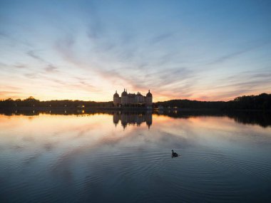 Schloss Moritzburg Barok kalesinin Saksonya Almanya 'sındaki Schlossteich gölü adasındaki günbatımı yansıması.