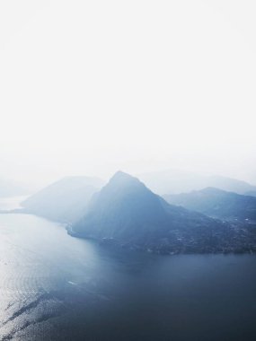 Monte Bre 'den Monte San Salvatore dağ tepesinin Ticino İsviçre' deki Lago di Lugano gölündeki panorama manzarası.