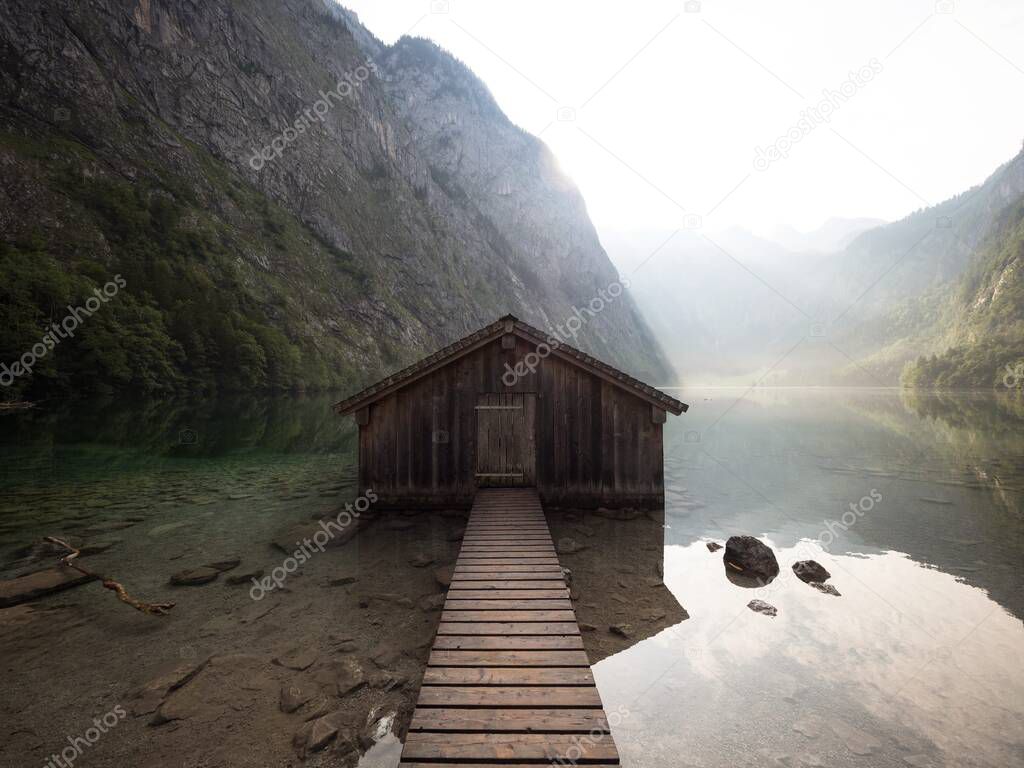 Panorama reflection of old wooden boat house shed alpine mountain lake Obersee Koenigssee Berchtesgaden Bavaria Germany