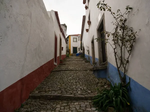 Panorama vista de las antiguas paredes blancas históricas casas edificios estrecha callejuela adoquinada calle callejón en Obidos Portugal —  Fotos de Stock