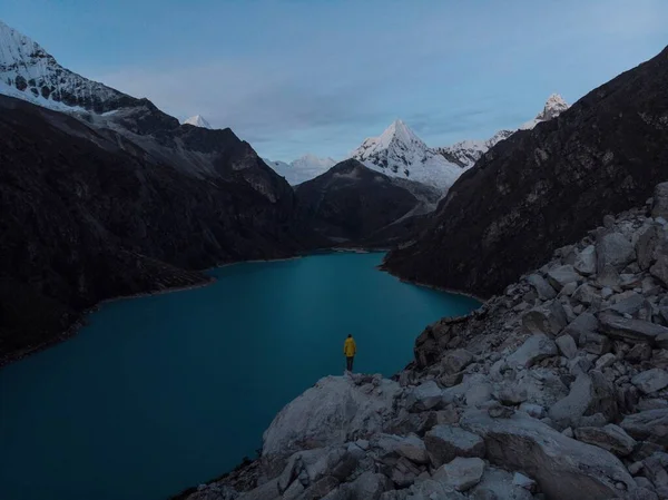 Wandelaar in geel jasje bij het blauw turquoise bergmeer Laguna Paron in Caraz Huaraz Ancash Cordillera Blanca Peru — Stockfoto