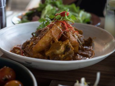 Öküz kuyruğu yahnisi singapore körili maydanoz garnitür tabağı ahşap restoran masası Ubud Bali Endonezya Asya 'da yemek pişirme lezzeti