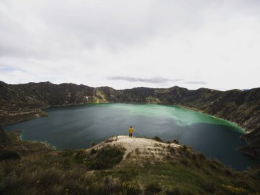 Sarı ceketli genç erkek yürüyüşçü Pujili Cotopaxi Andes Güney Amerika 'daki Quilotoa gölü krater çemberinde.