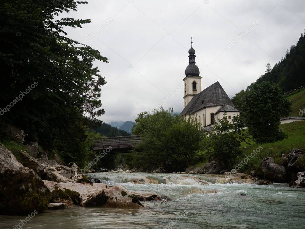 Idyllic rural alpine mountain chapel parish church St Sebastian at Ramsauer Ache river stream in Ramsau Berchtesgaden Upper Bavaria Germany Europe