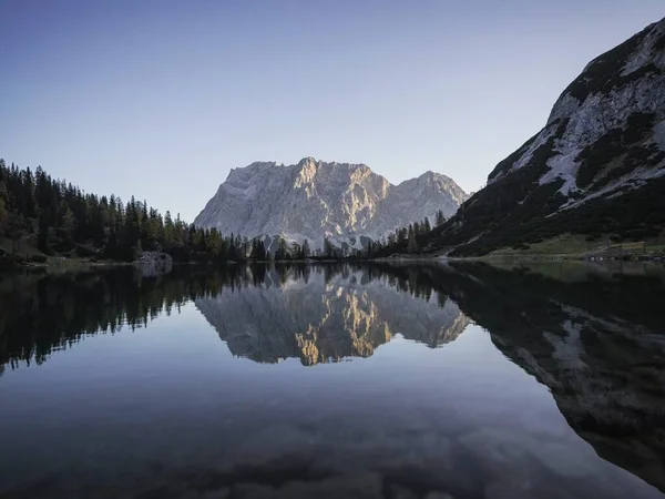 Sunrise mirror reflection panorama of Zugspitze mountain massif in clear calm transparent alpine lake Seebensee in Ehrwald Tyrol Austria alps Europe