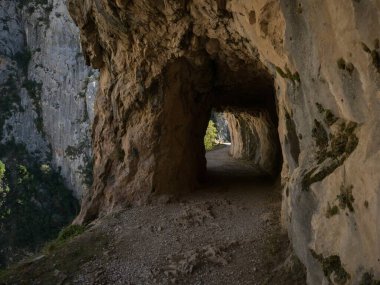 Natural tunnel hole on gorge valley canyon hiking trail path route Senda del Cares in Picos de Europa mountain range Poncebos to Cain in Leon Asturias, Spain Europe