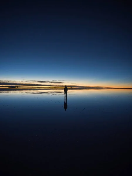 在南美洲波托西玻利维亚的Salar Uyuni盐滩湖上 一位孤独的男性游客欣赏安第斯山脉日出全景倒影 — 图库照片