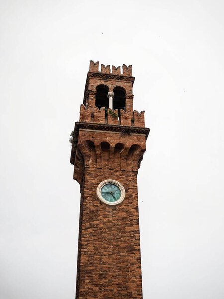 Closeup view of Torre dell Orologio brick church bell clock tower on Campo Santo Stefano in Murano Venice Venezia Veneto Italy Europe