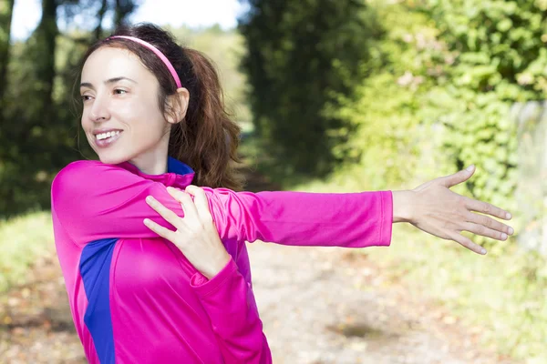 Sportliche Frau streckt Arm im Wald aus — Stockfoto