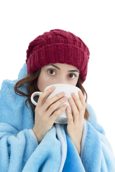 Woman warming herself under a blanket and with a cup of tea — Stock Photo, Image