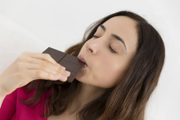 Woman biting a piece of dark chocolate — Stock Photo, Image