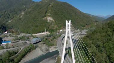 Ormanlarla çevrili fırtınalı bir nehrin üstündeki dağ geçidinde yüksek hızlı bir otoyolun üzerinde uçuyorlar. Arabanızla seyahat edin. Dağ nehri üzerindeki modern köprünün güzel manzarası..