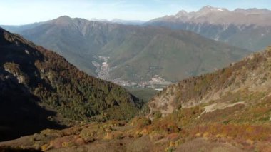 Sonbaharda dağlardaki güzel ormanın üzerinde hava manzaralı bir uçuş. Gün batımında dağların renkli manzarası. Dağlarda gezin ve eğlenin