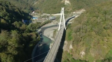 Ormanlarla çevrili fırtınalı bir nehrin üstündeki dağ geçidinde yüksek hızlı bir otoyolun üzerinde uçuyorlar. Arabanızla seyahat edin. Dağ nehri üzerindeki modern köprünün güzel manzarası..