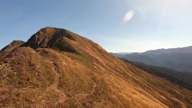 Dağ manzarasının renkli manzarası sonbaharda altındır. Dağlardaki sonbahar ormanlarının güzel manzarası parlak mavi bir gökyüzünün arka planına karşı