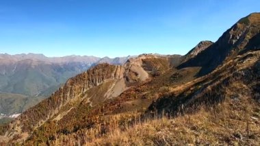 Dağ manzarasının renkli manzarası sonbaharda altındır. Dağlardaki sonbahar ormanlarının güzel manzarası parlak mavi bir gökyüzünün arka planına karşı